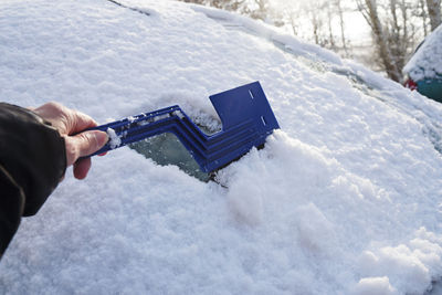 Cropped hand cleaning snow from glass