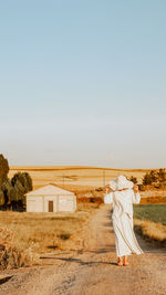 Rear view of woman standing on field against clear sky