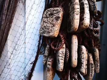 Close-up of fishing net with buoys by wall