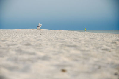 Mid distance view of hooded beach chair at beach against blue sky