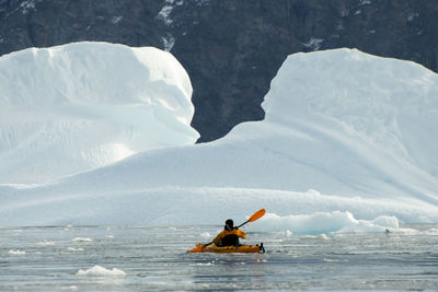 Rear view of person in boat on sea during winter