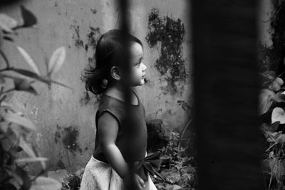 Girl looking away while standing against wall