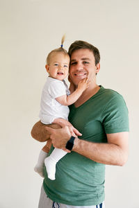 Father holding baby against white background
