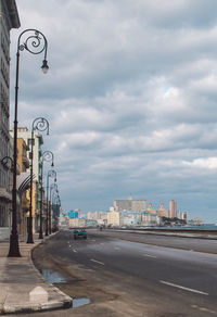 Road by buildings against sky in city