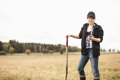 Mid adult female farmer using mobile phone in field