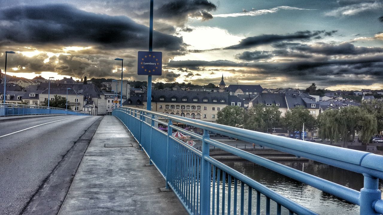 architecture, building exterior, built structure, sky, city, cloud - sky, cityscape, cloudy, railing, cloud, residential district, city life, residential building, bridge - man made structure, transportation, the way forward, high angle view, residential structure, connection, river