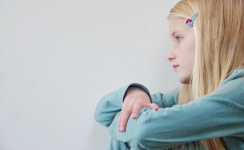 Side view of sad girl against white background