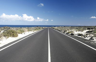 Empty road amidst landscape leading towards sea