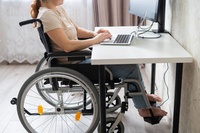 Midsection of woman using laptop on table