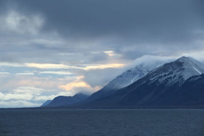 Scenic view of sea and snowcapped mountains against sky