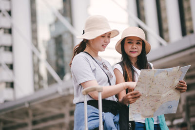 Tourists reading map while standing in city