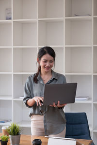 Young woman using phone while standing on table