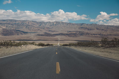 Road by mountains against sky