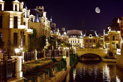 Bridge over canal amidst buildings at night