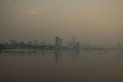 Scenic view of river and buildings against sky during sunset