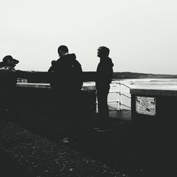 Silhouette people standing on beach against clear sky