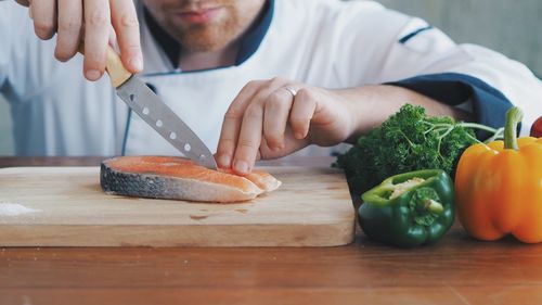 Midsection of man preparing food on cutting board