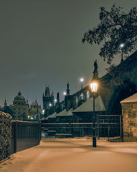 Illuminated street light in city against sky at night