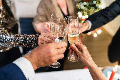 From above of unrecognizable group of people clinking glasses with champagne during christmas party at home