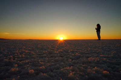 Person standing at bonneville salt flats during sunset