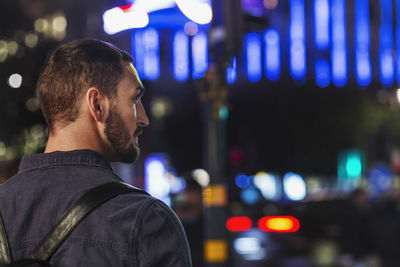 Rear view of man standing in city at night