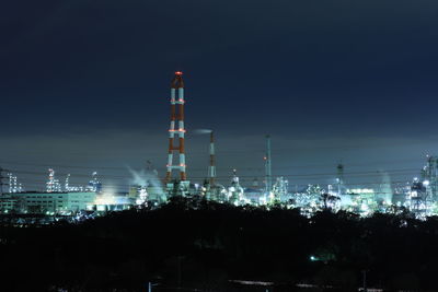 Illuminated factory against sky at night