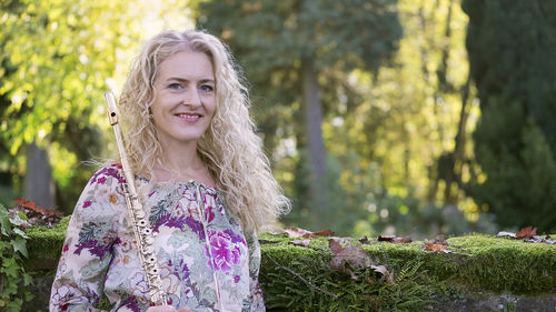 Portrait of smiling woman holding flute outdoors