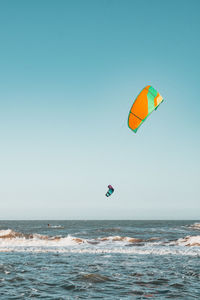 Scenic view of kitesurfing on sea against clear sky