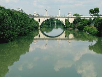 Arch bridge over river against sky