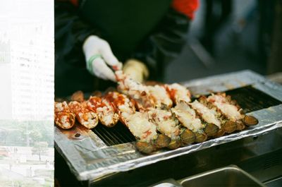 Close-up of man holding meat on barbeque grill