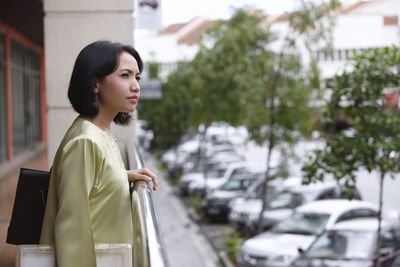 Thoughtful woman holding purse while standing in corridor