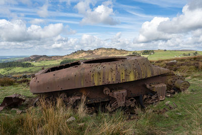 Abandoned car on field against sky