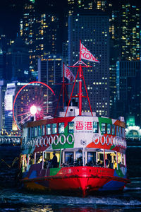 Information sign in river against illuminated city at night