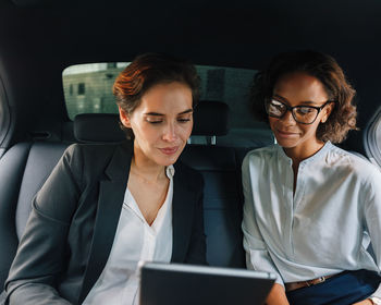 Mid adult woman using mobile phone while sitting in car