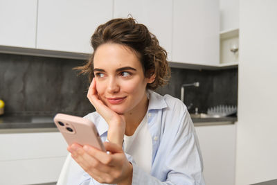 Portrait of young woman using mobile phone at home