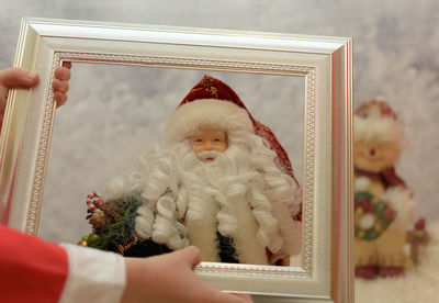 Cropped hands holding frame by santa claus figurine