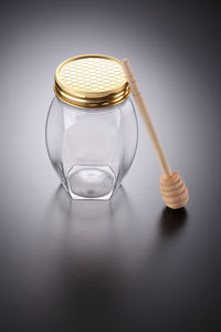 Glass jar and honey dipper on gray background