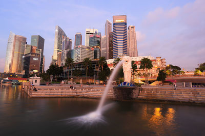 Modern buildings by river against sky in city