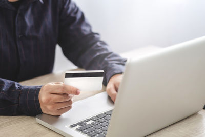 Midsection of man using laptop on table