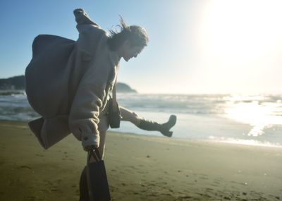 Man standing on beach against sky during sunset