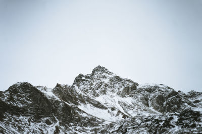 Low angle view of snowcapped mountains against clear sky