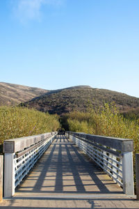 Scenic view of bridge in front of mountains against clear blue sky