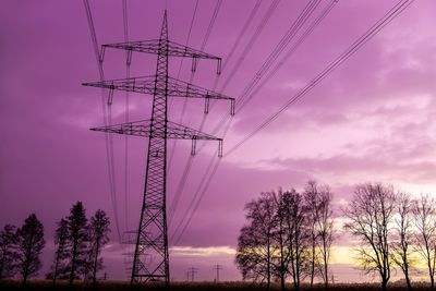 Low angle view of silhouette electricity pylon against sky at sunset