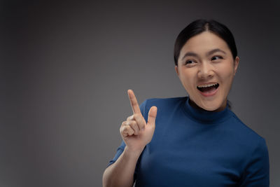 Portrait of smiling young woman against gray background
