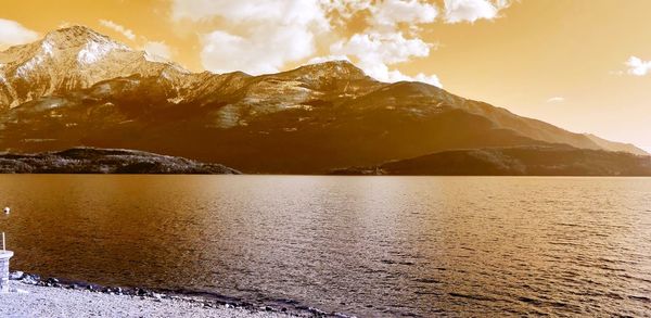 Scenic view of sea by mountains against sky