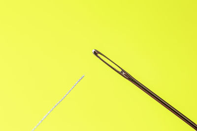 Close-up of needle and thread on yellow background