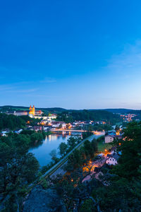 High angle view of illuminated buildings against blue sky