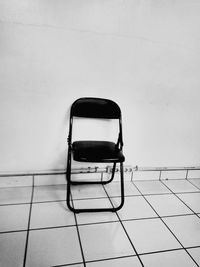 Empty chair against white wall