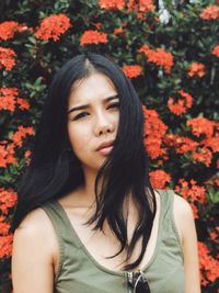 Portrait of beautiful young woman standing against plants