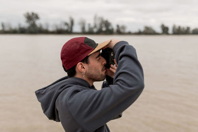 Side view of man photographing by lake